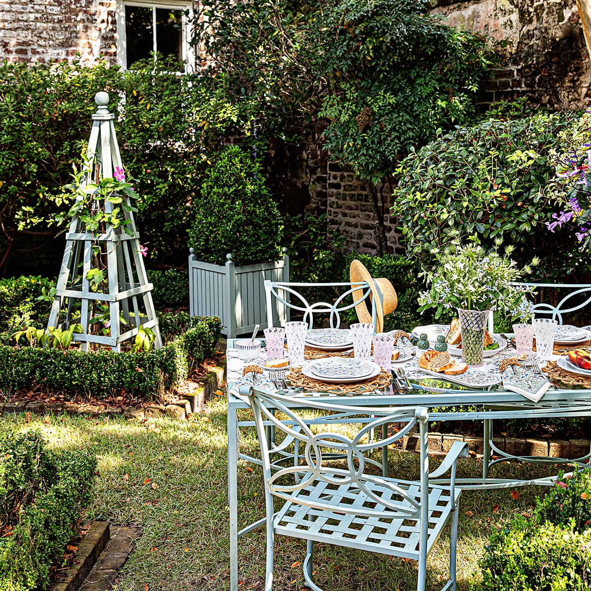 Al fresco tablescape in the middle of a garden featuring trellis glassware and villa seville ceramics