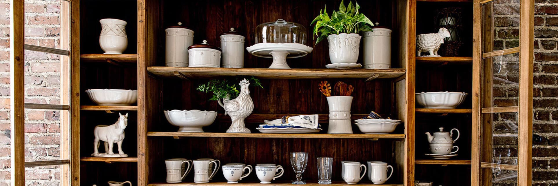 A wooden cabinet filled with ceramic stoneware dinnerware.