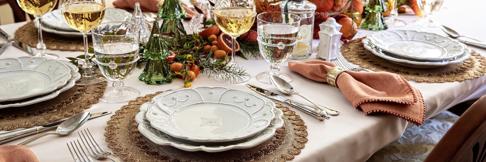 Jardins du Monde place setting sits on the top of a gold placemat with glass Christmas trees as a centerpiece.