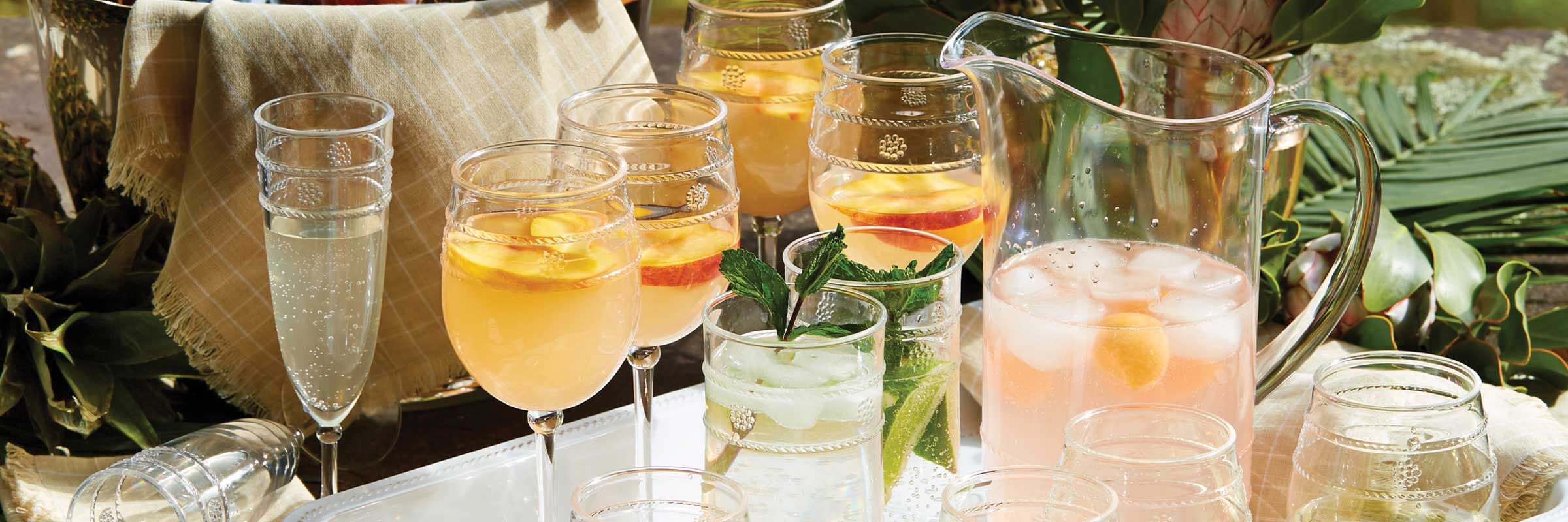 Party refreshments in acrylic wine, tumblers and stemless glasses are prepped for party-goers on a white melamine tray.