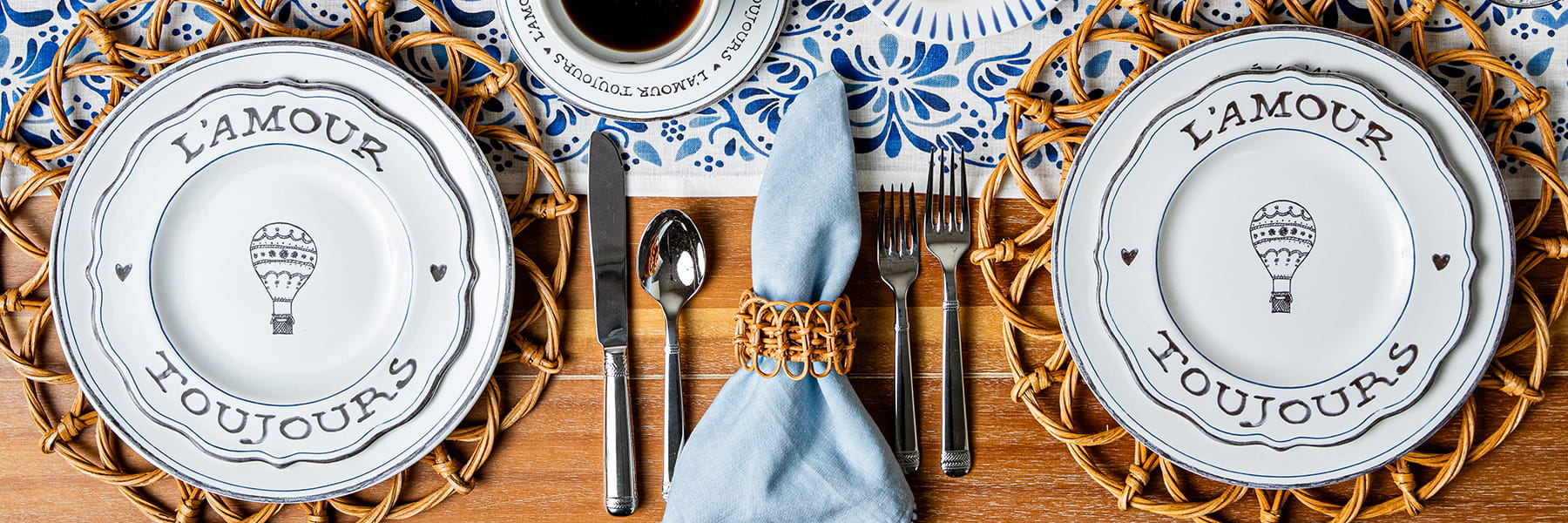 Two L'Amour Toujours plates on a rattan placemat on top of a blue table runner