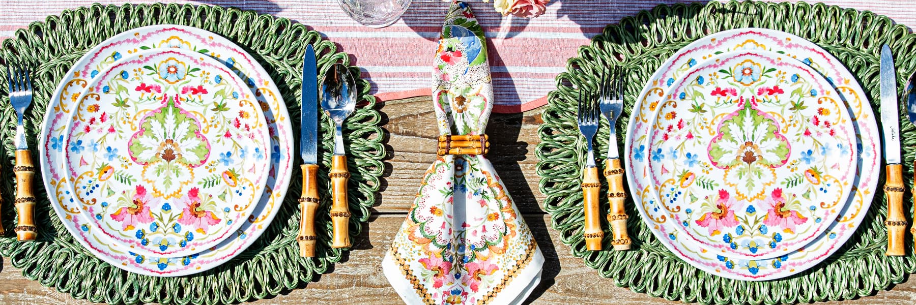 Juliska Sofia plates and napkin on top of a green rattan placemat