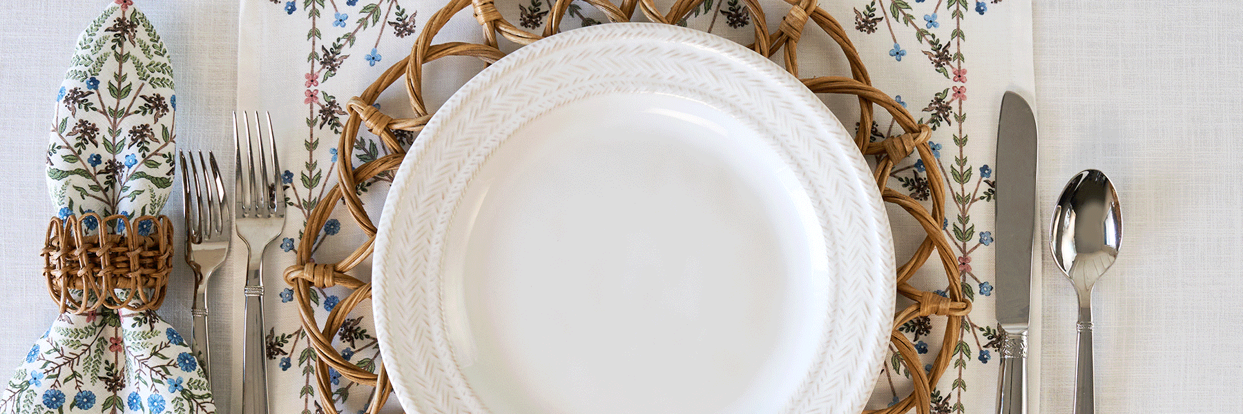 Moveable gif of Villa Seville collection, Sitio Stripe blue plates, and Le Panier whitewash against a rattan placemat.