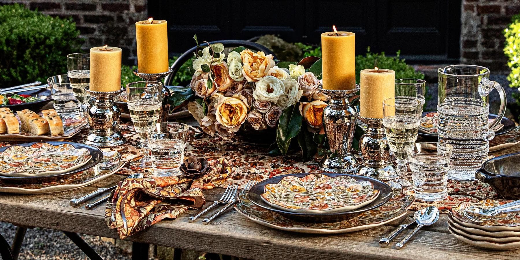 Dining table set for a meal with candles, flowers, and place settings.