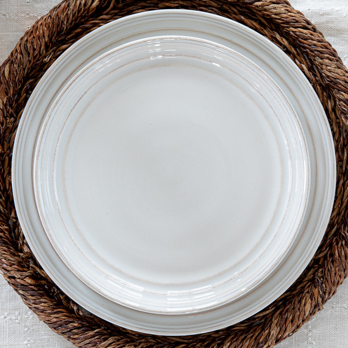 Bilbao Whitewash collection stacked plates on a brown charger.