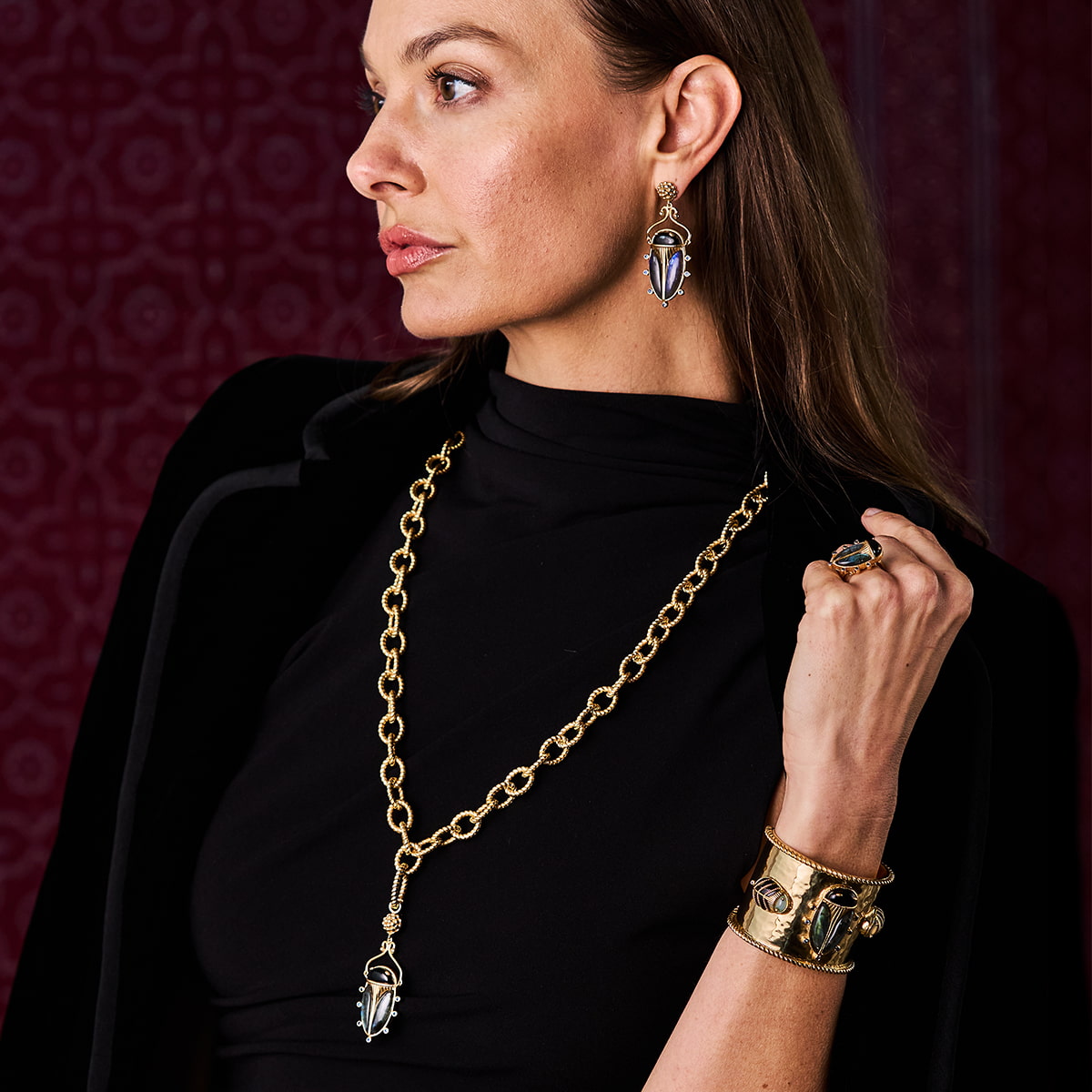 Woman posing in a black coat wearing blue labradorite jewelry