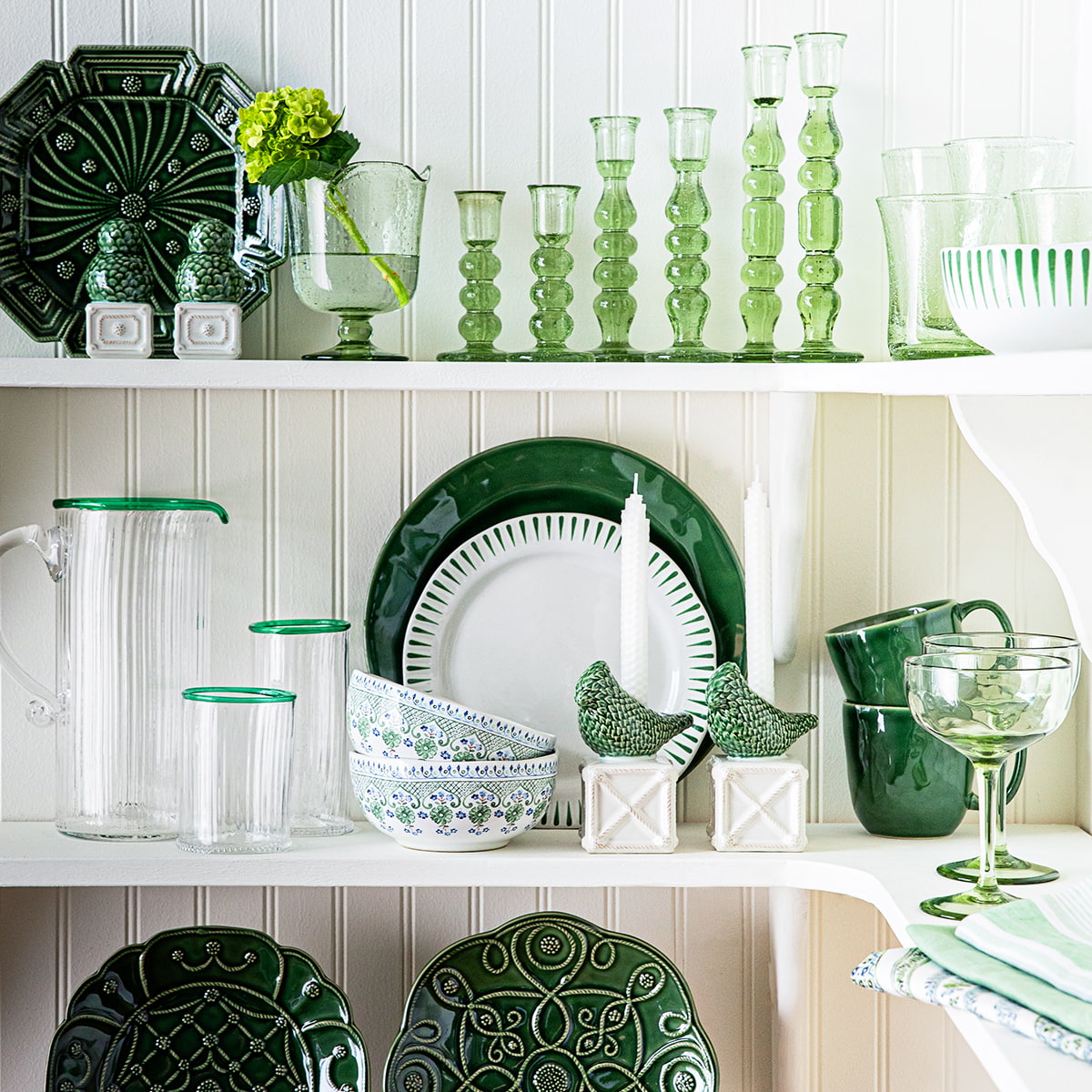 Cabinets filled with green Juliska serveware, glassware, plates, and linens