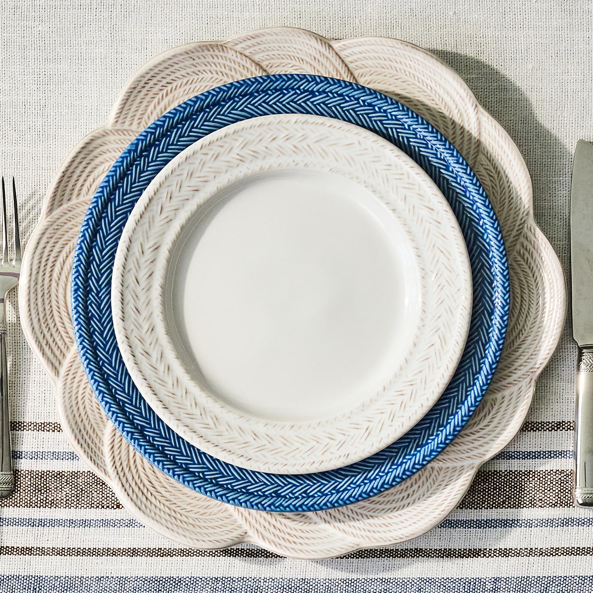 Stack of white and blue plates on a textured tablecloth