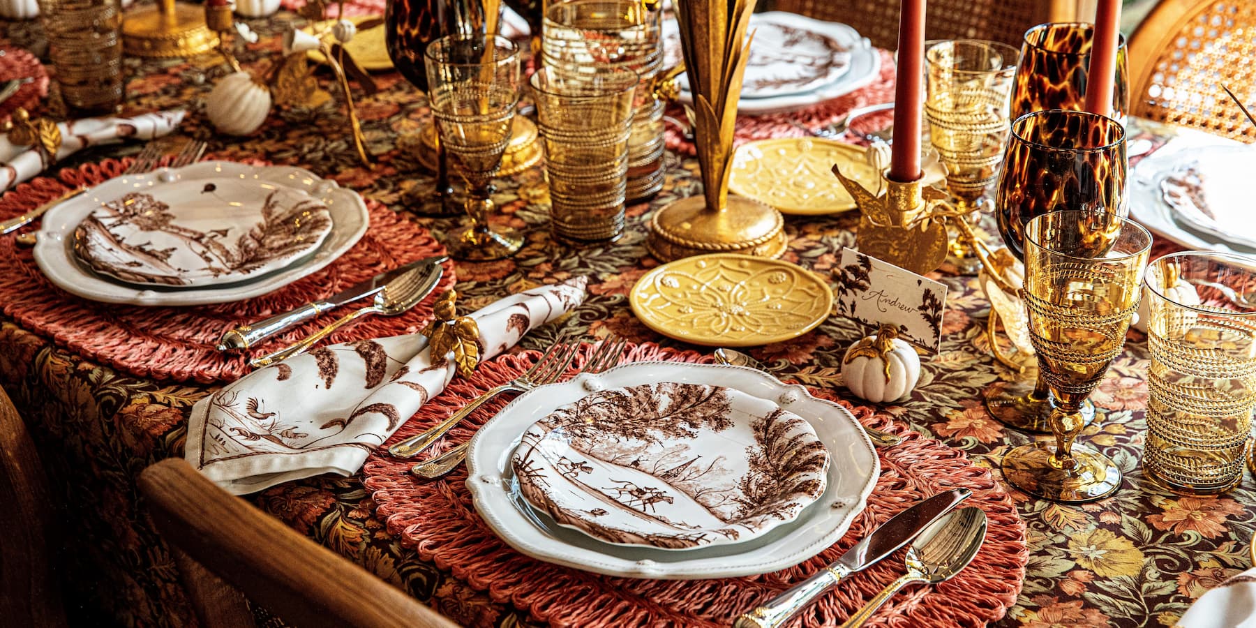 Decorative table setting with plates, glasses, and cutlery on a patterned tablecloth.