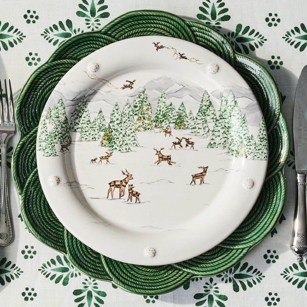 Moveable gif with set of decorative plates with winter scene design on a patterned tablecloth