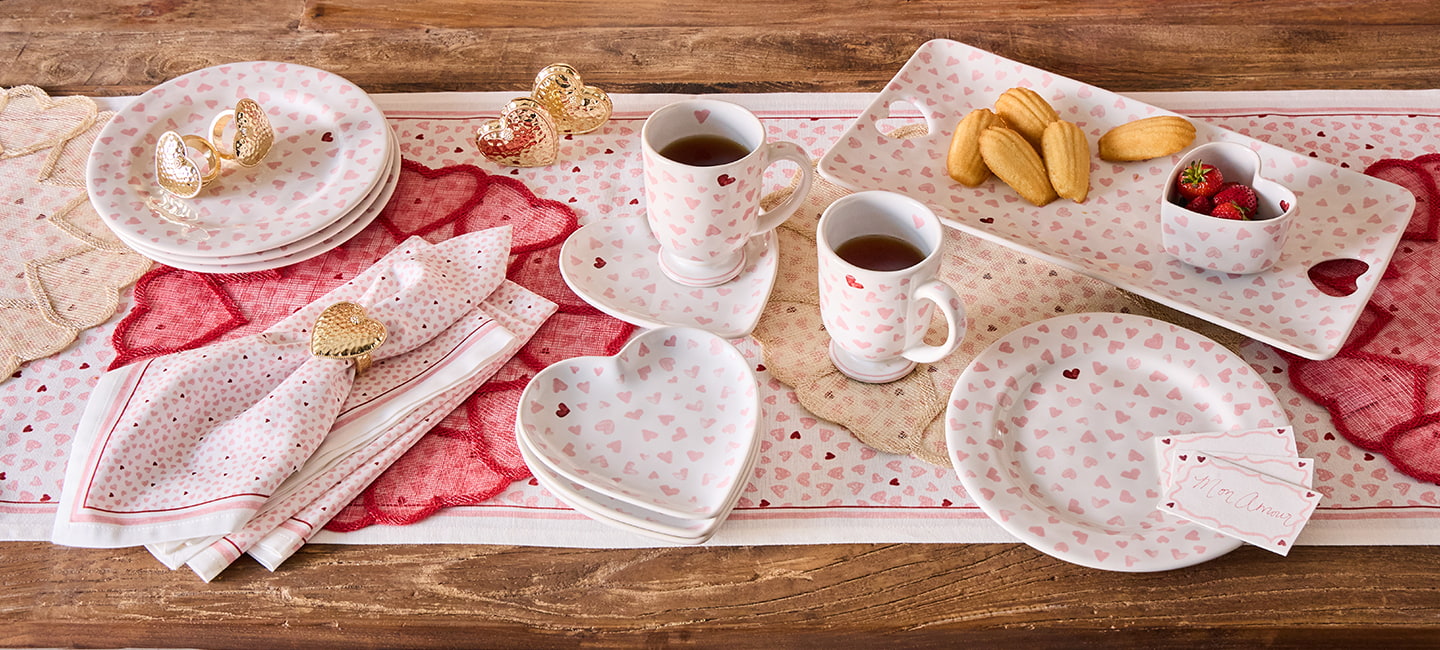 Dining table setting with ceramic plates, cups, and pastries on a wooden surface.