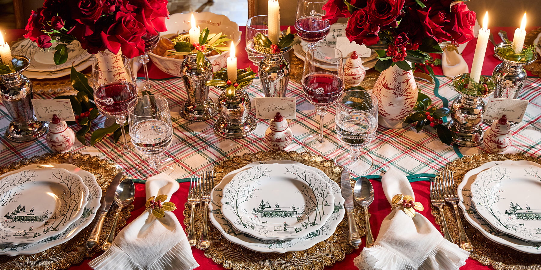 Decorative table setting with plates, napkins, and candles on a plaid tablecloth.