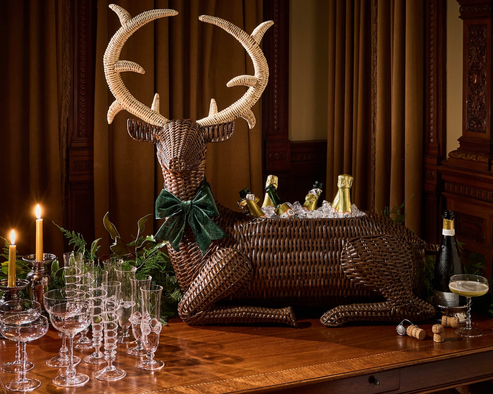 Decorative wicker deer head with ice bucket and drinks on a wooden table.