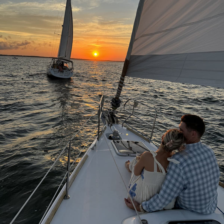 Image of engaged couple on sail boat at sunset.