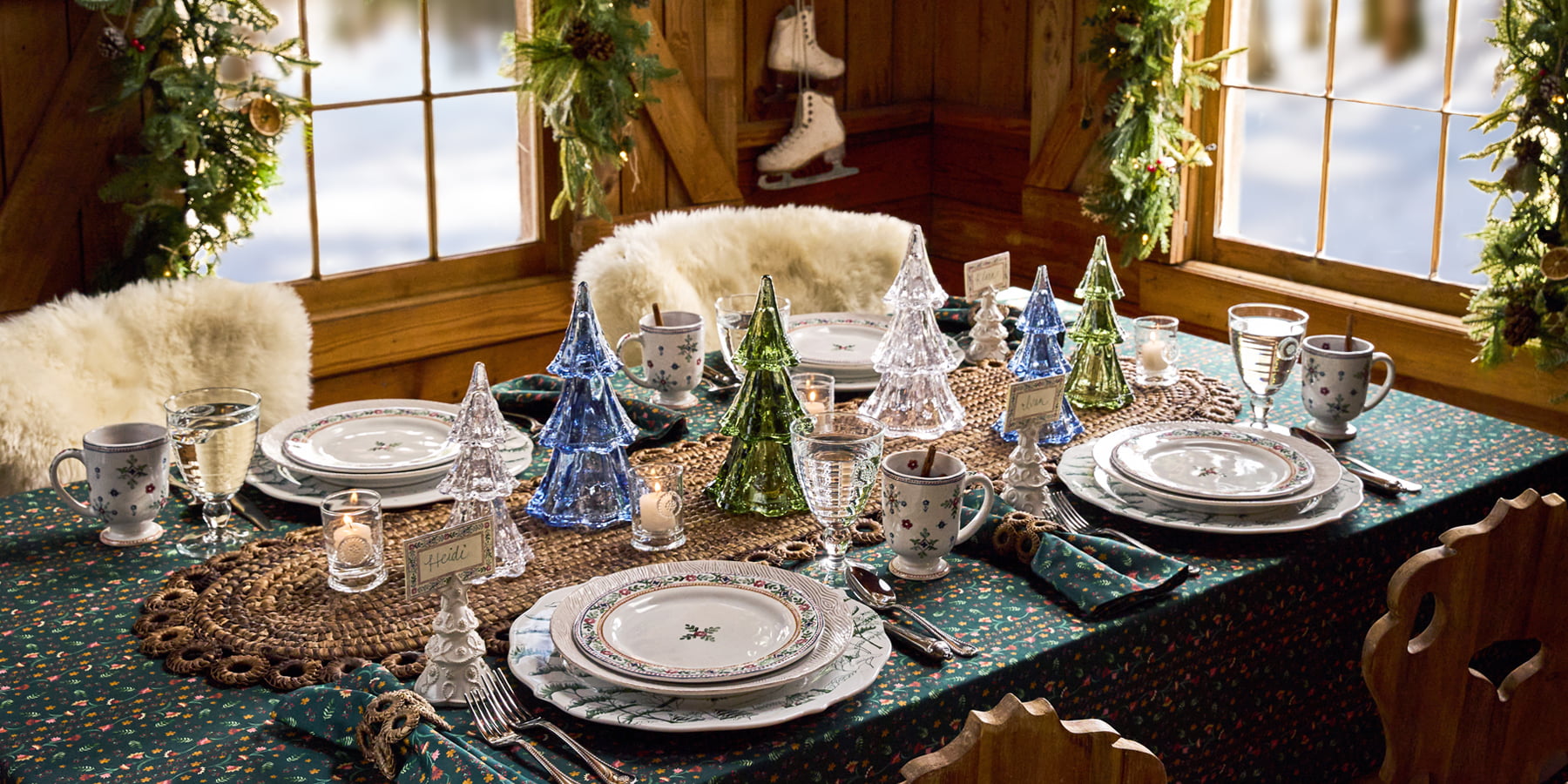 Decorated dining table with Christmas-themed glasses and plates in a cozy room.