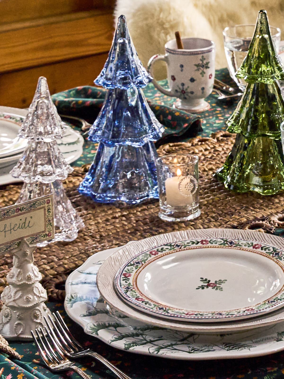 Decorative table setting with Christmas tree-shaped candle holders and patterned plates.