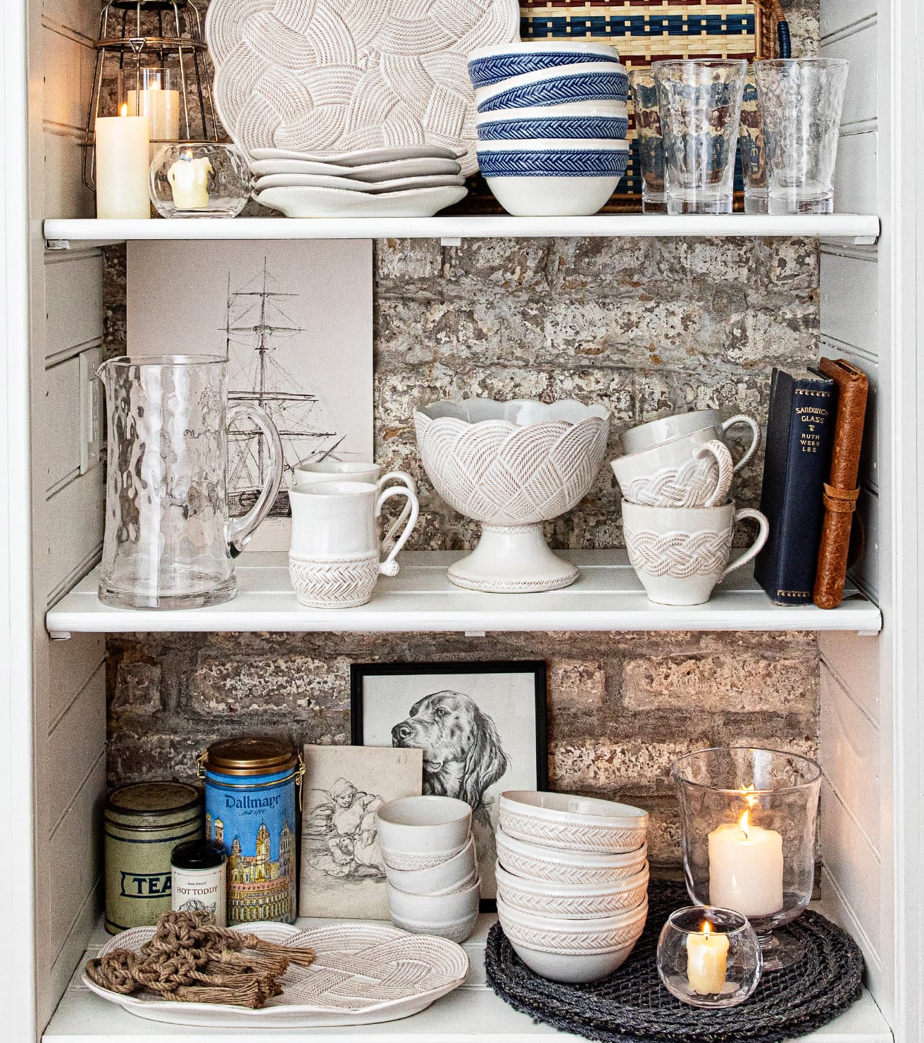 Shelving unit with decorative items including bowls, mugs, and candles against a textured wall.