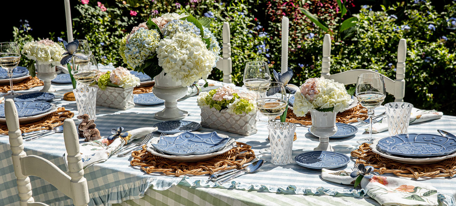 Elegant outdoor dining table setting with floral arrangements and luxe ceramics.