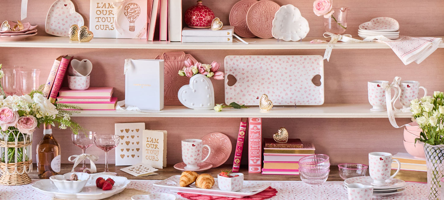 Shelves with decorative items including books, vases, and trinkets against a pink wall.