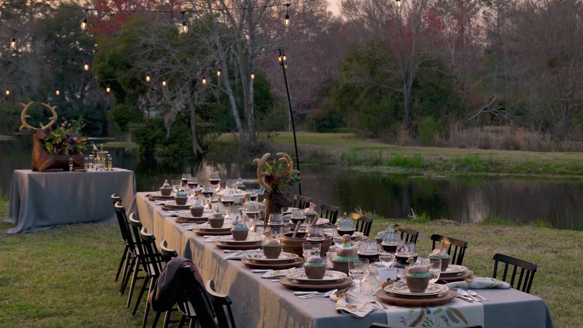 Load video: A video of Thanksgiving table setting with wine glasses, plates, and decorative elements outdoors.