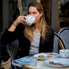 Woman sips tea at a Parisian café.
