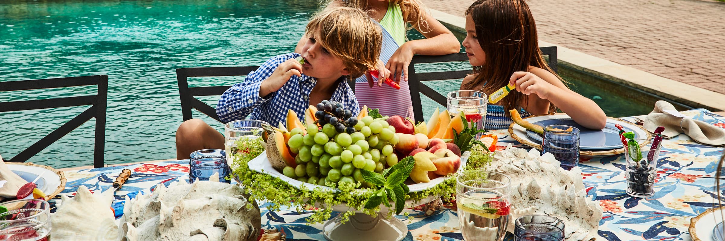 A festive red, white and blue tablecloth with a Bamboo rimmed dinner plate with a Chambray Melamine salad plate on top.