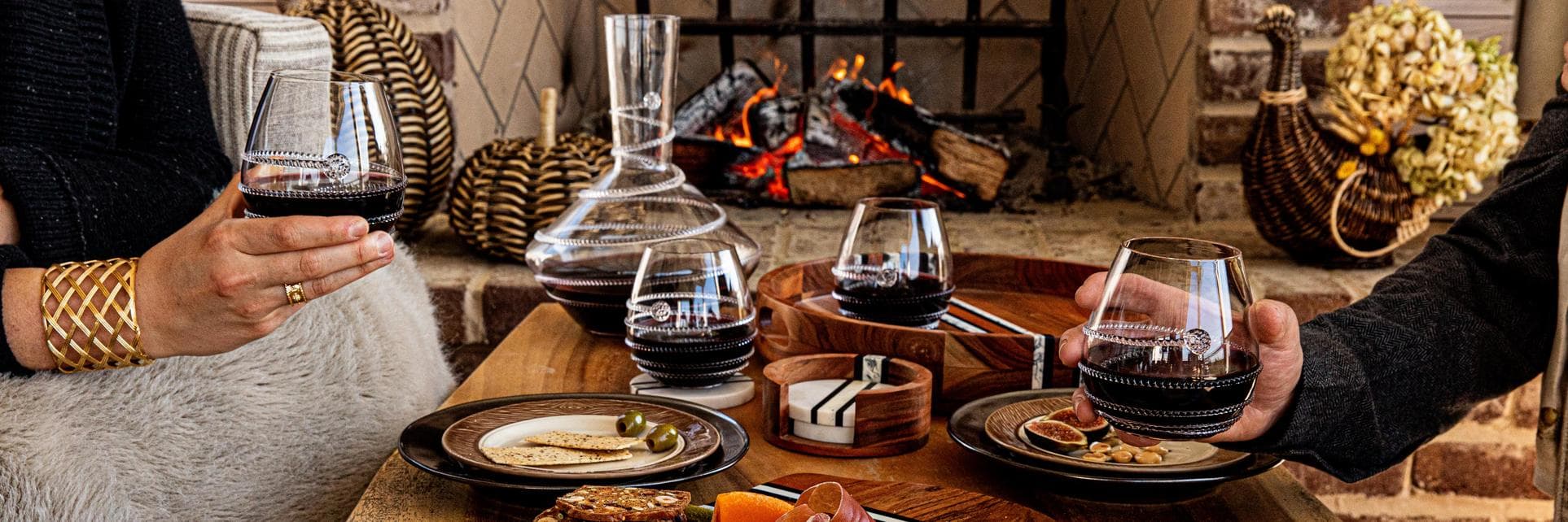 Friends cheers wine glasses over a coffee table full of yummy snacks.