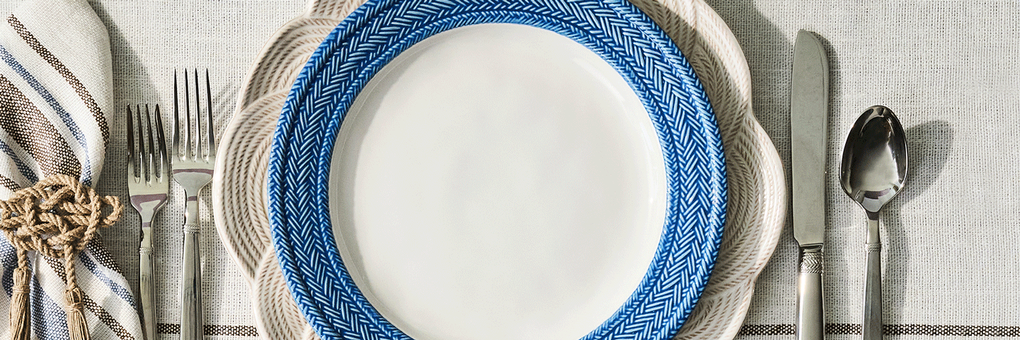 Moveable gif featuring stack of white and blue plates on a textured tablecloth with silver flatware