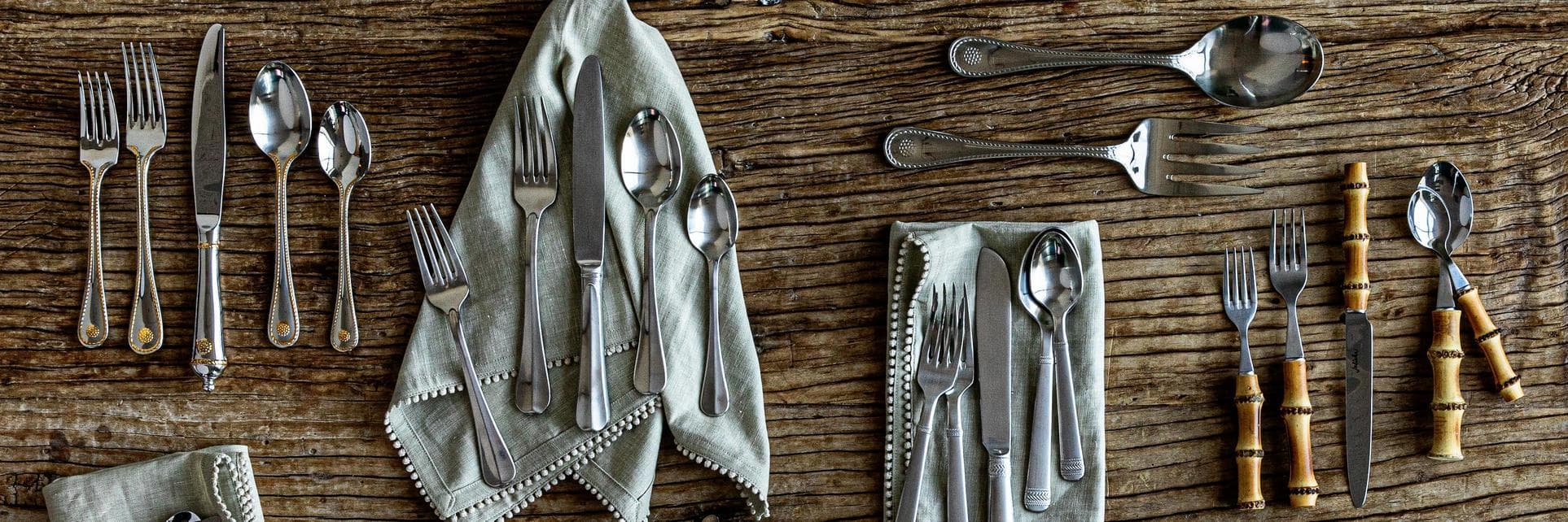 Flatware collections laid out on a rustic wooden table.