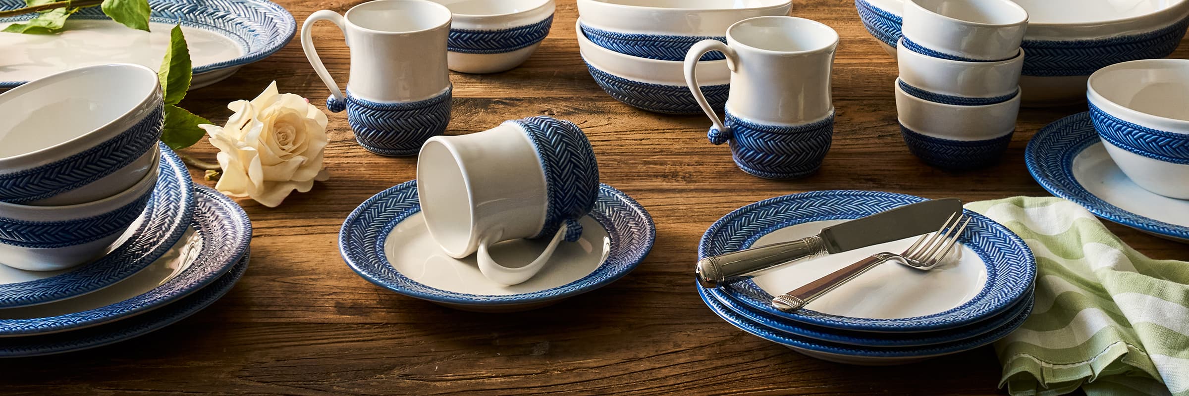 Le Panier place setting stacked on top of a striped tablecloth