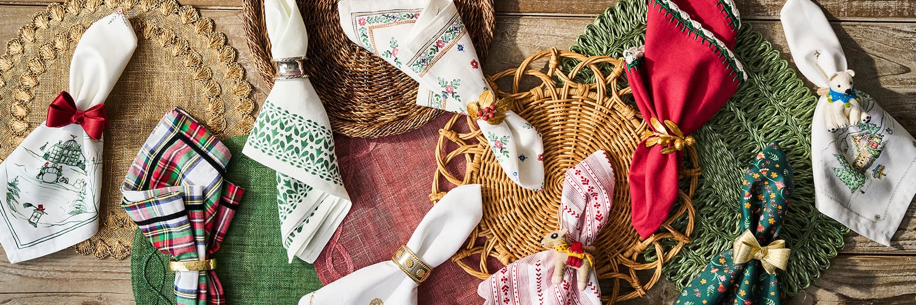 Variety of Juliska placemats and napkins lined up on a green tablecloth