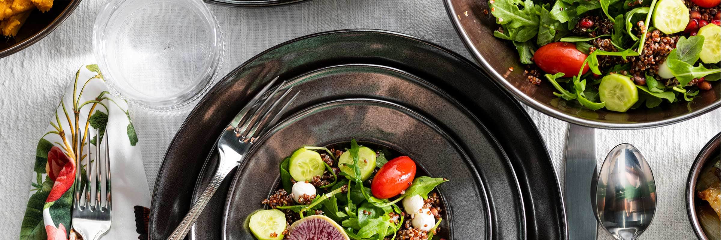 Three stacked Pewter Stoneware plates within a place setting