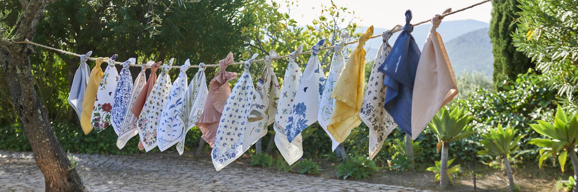 Multiple different napkins, tied to a clothesline, blow in the wind.