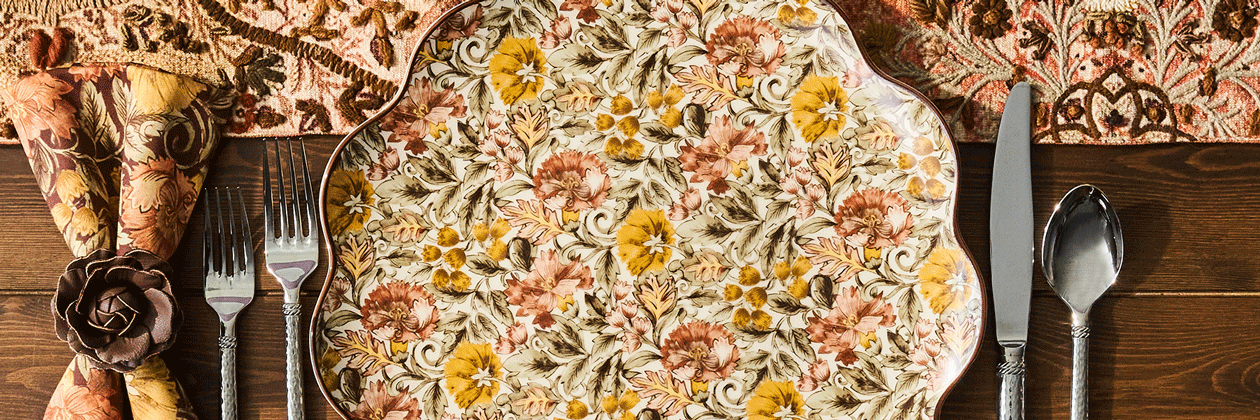 Movable gif featuring decorative floral plate and alternating dessert plates on a wooden table with a patterned tablecloth.