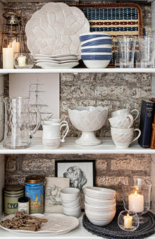 Shelves with decorative ceramic items against a rustic brick wall.