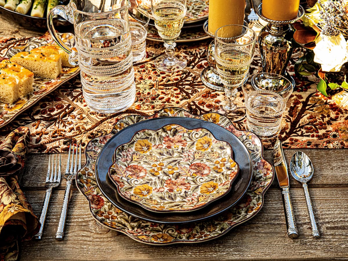 Dinner table setting with a pizza, glasses, and cutlery on a wooden surface.