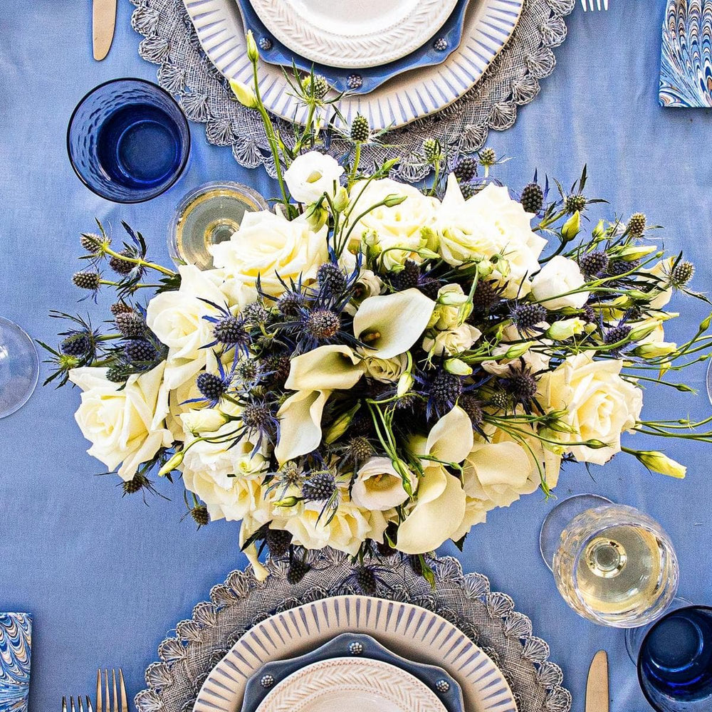 Overhead image of a large white and blue flower arrangement in the center of a blue and white tablescape.