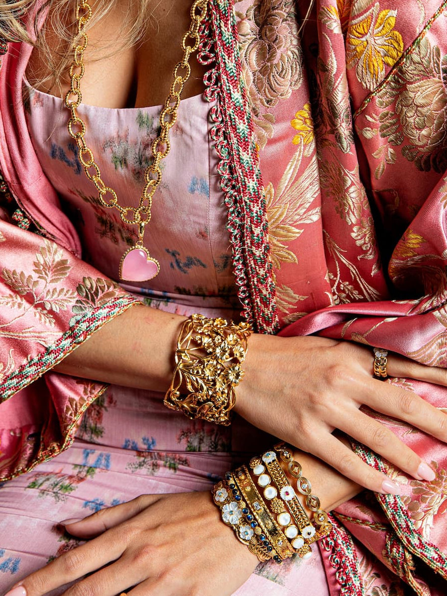 Person wearing a pink embroidered outfit with gold jewelry