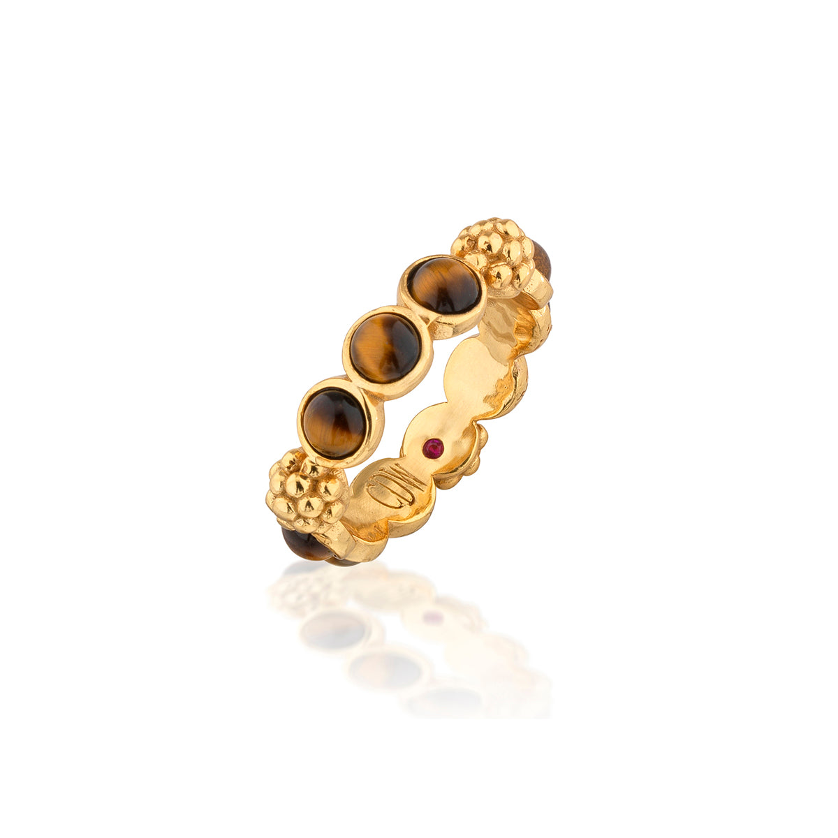 A gold band ring featuring four round brown tiger's eye stones and a small red gemstone, displayed on a clean white background with a soft reflection.