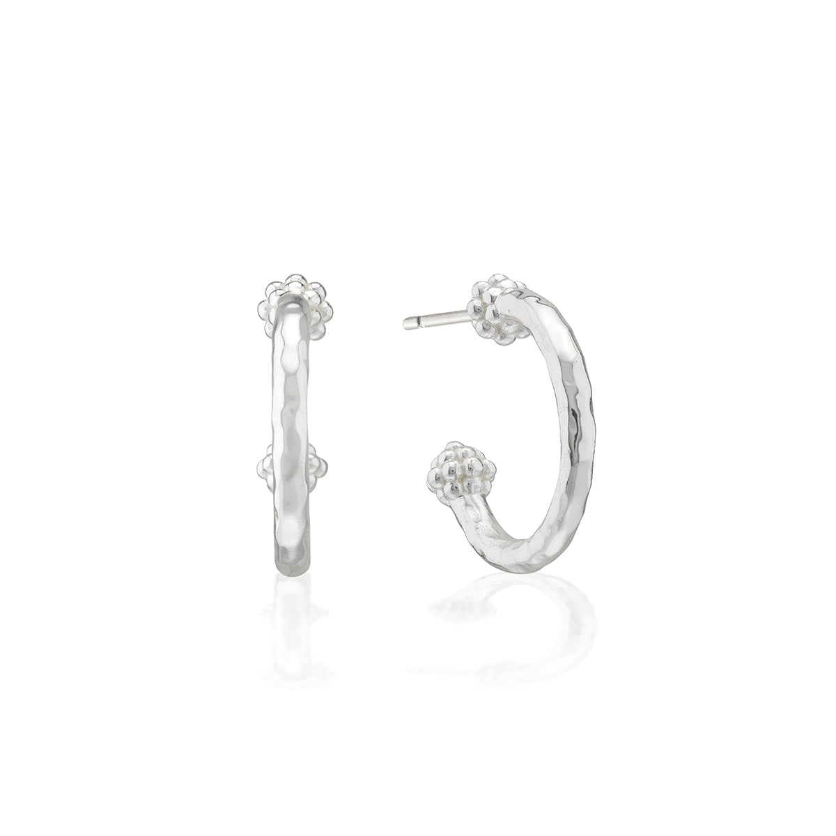 A pair of silver hoop earrings with textured hammered finishes and small floral details at the top and bottom, shown on a clean white background with a soft reflection.