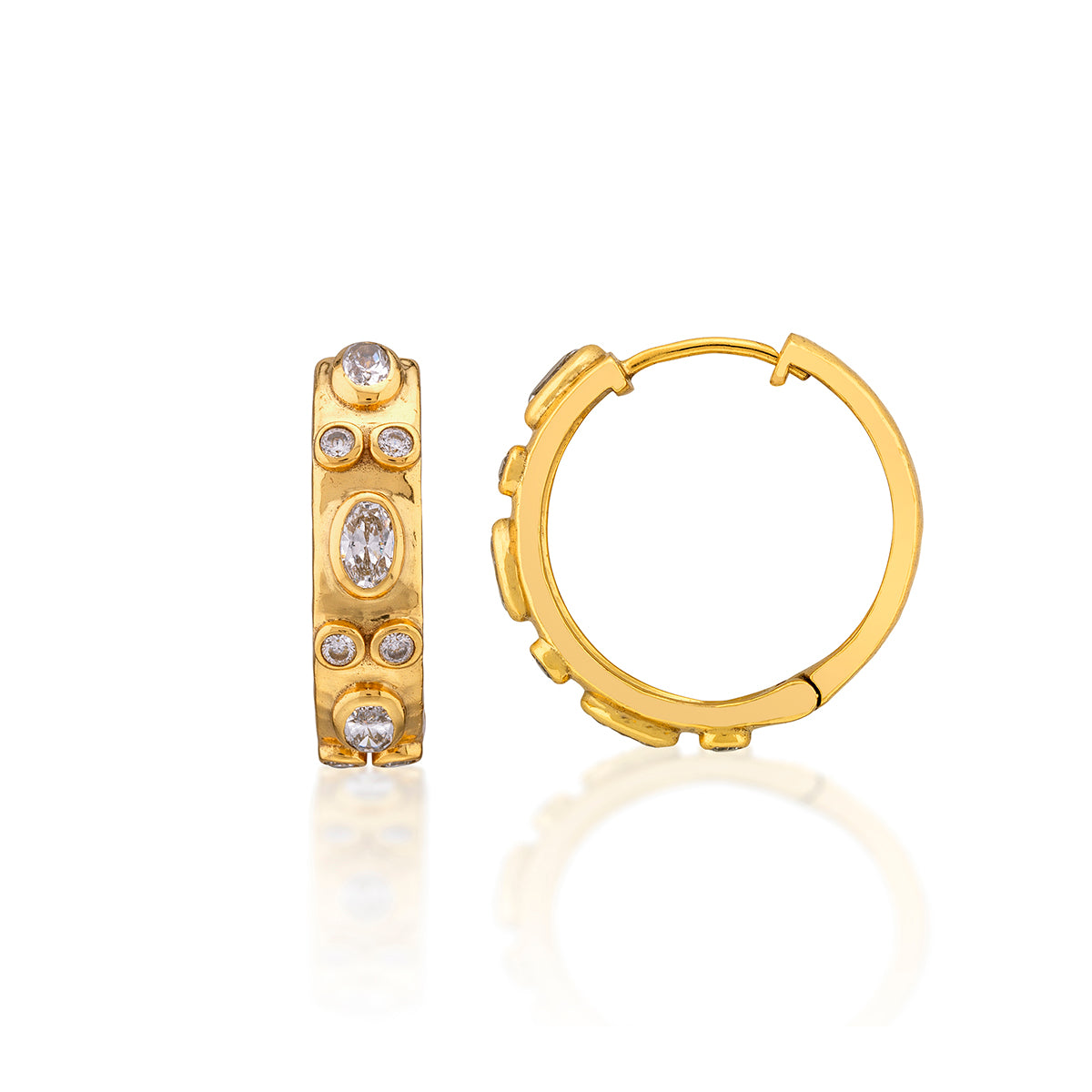 A pair of gold huggie hoop earrings, one shown from the front with a vertical bar set with oval and round clear gemstones, and the other from the side showing the huggie profile, on a white background with a soft reflection.