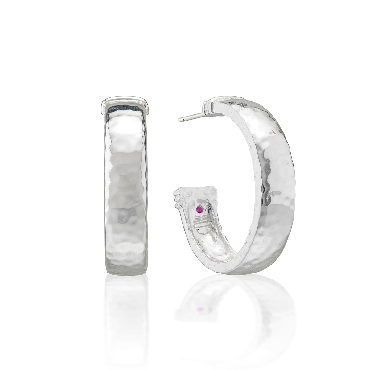 A pair of hammered silver hoop earrings, one shown from the front and the other from the side/back, featuring a small purple gemstone on the inner band, set against a white background with a soft reflection.