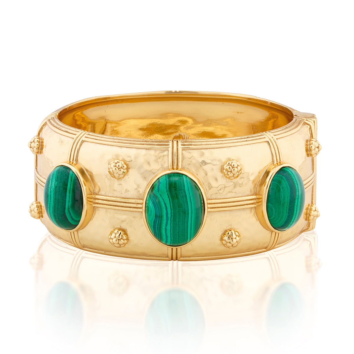 A wide gold bangle bracelet featuring three oval green malachite stone inlays and small gold floral accents, shown on a white background with a soft reflection.