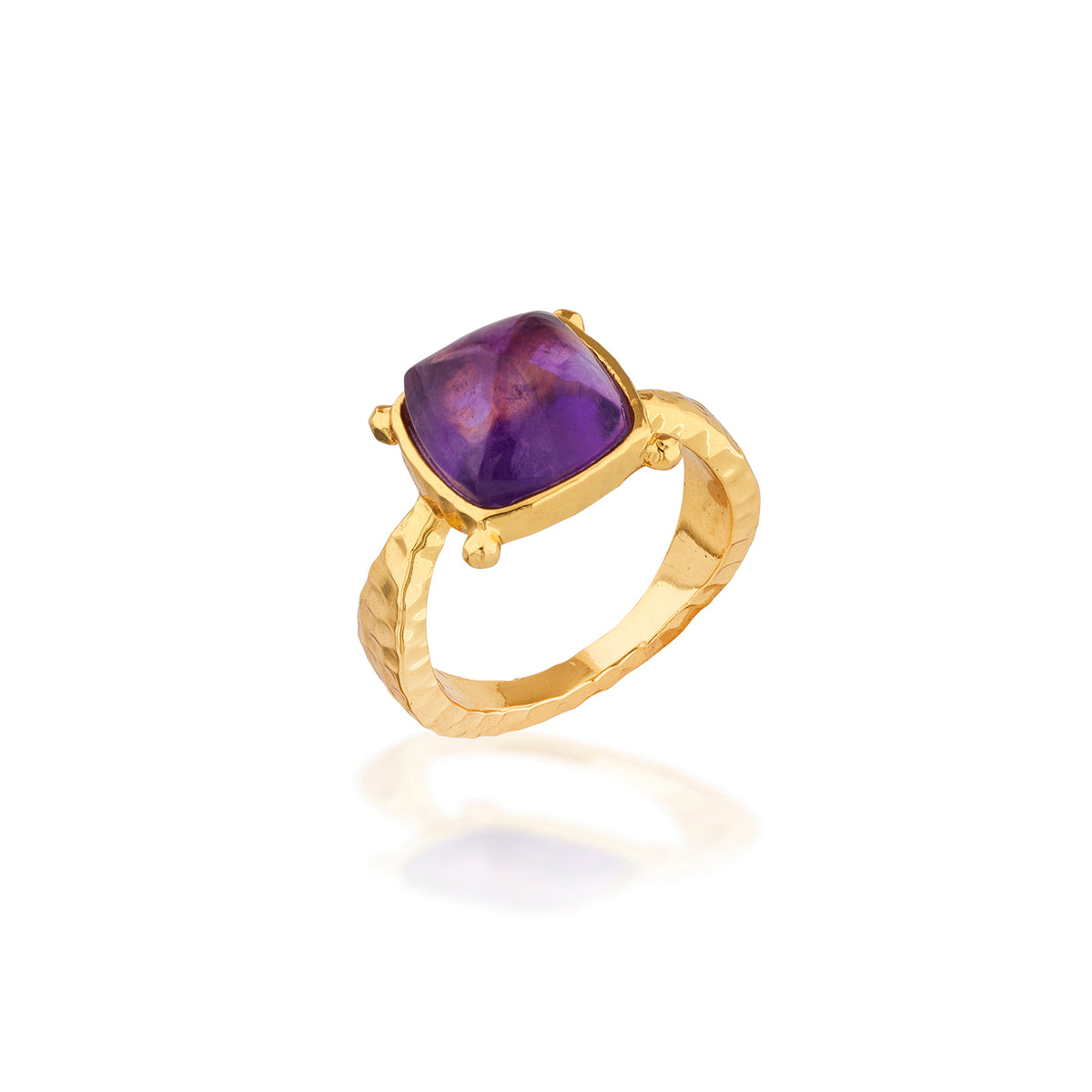 A gold ring featuring a cushion-cut purple amethyst gemstone in a prong setting, displayed on a clean white background with a soft reflection below.