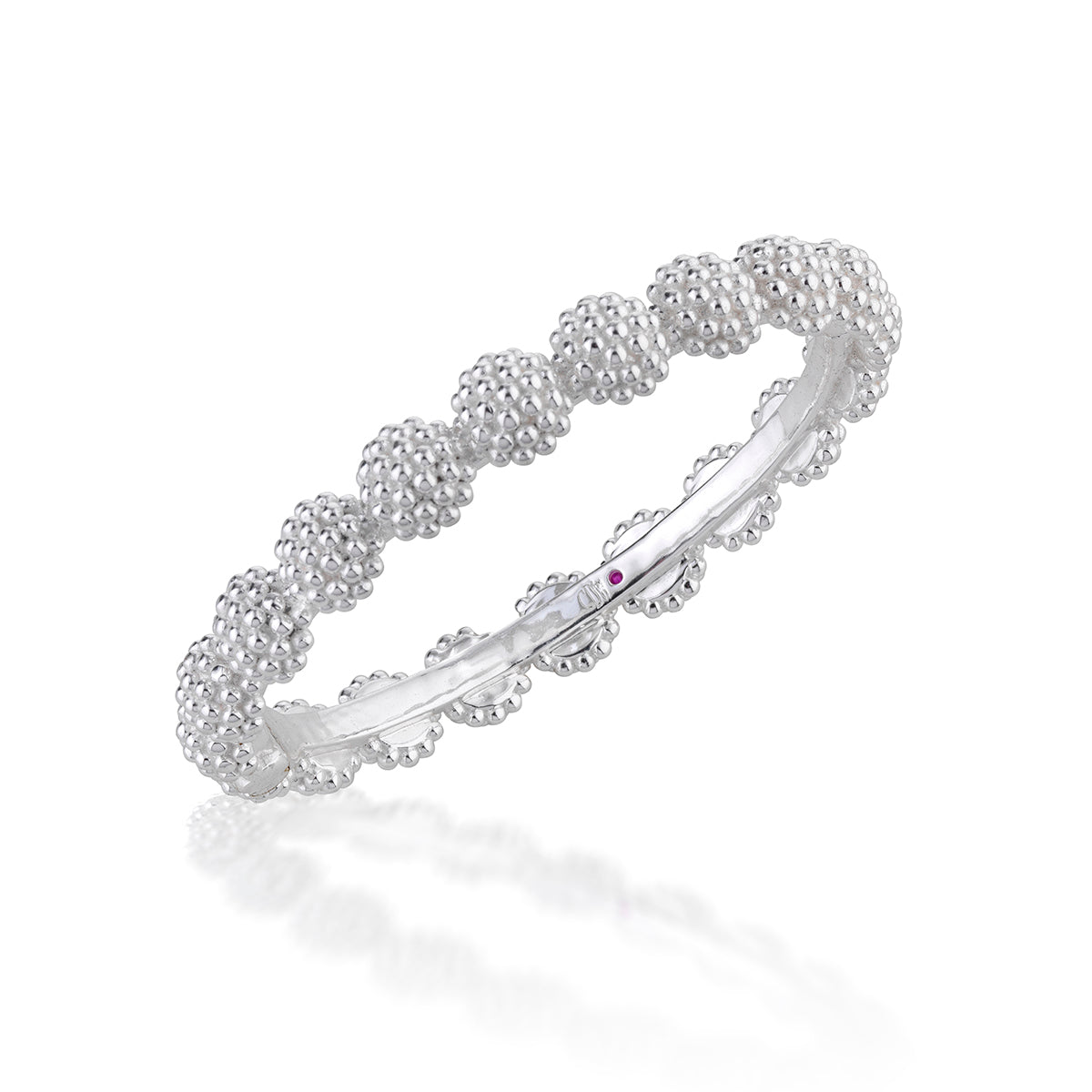 A silver bangle bracelet featuring a textured beaded pattern along the outer edge and a tiny purple accent stone on the inner band, shown on a white background with a soft reflection.