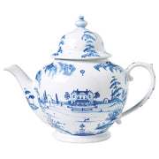 A white teapot with a blue design painted on it of a country estate.
