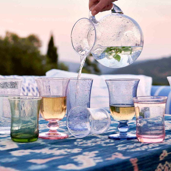 Person pouring water from the provence pitcher into provence goblets and tumblers