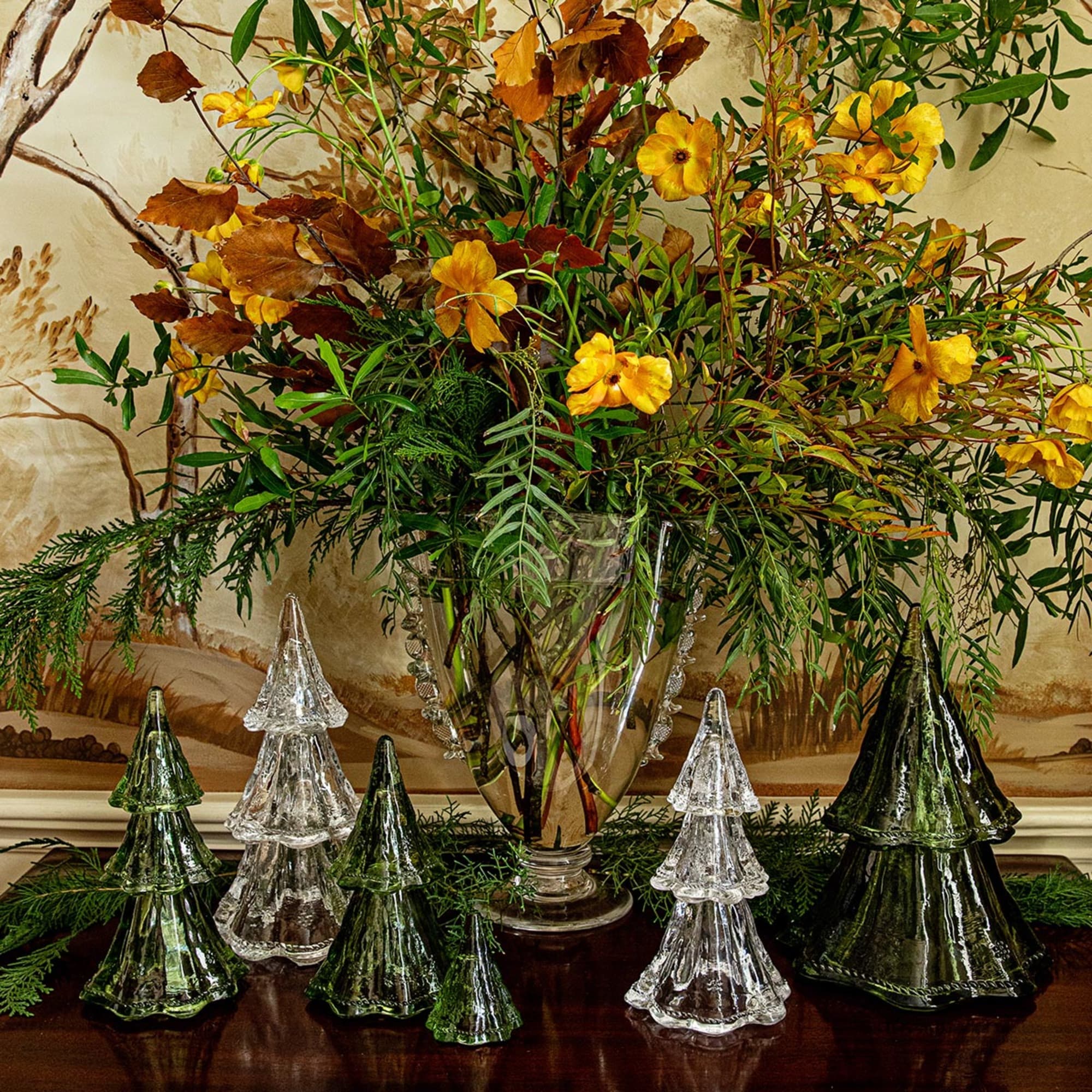 Decorative glass trees and a floral arrangement on a table with a decorative wall in the background.
