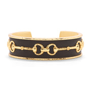 Gold cuff with a snaffle bit design over dark leather.