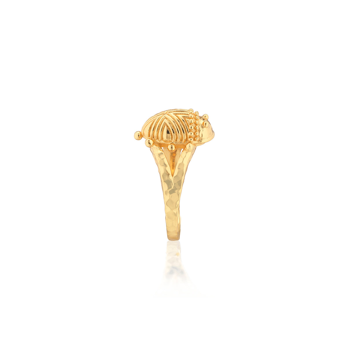 A gold ring featuring a sculpted, textured dome-shaped top with small bead details, shown on a plain white background with a soft reflection below.